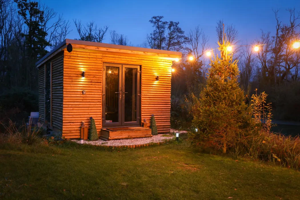 Welham luxury timber cabin illuminated at dusk